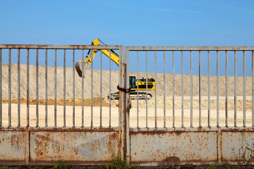Yellow excavator on a construction site against metal door