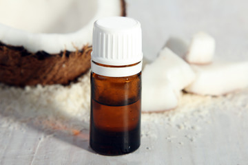 cut the coconut with coconut near the small bottle of liquid on a white wooden background
