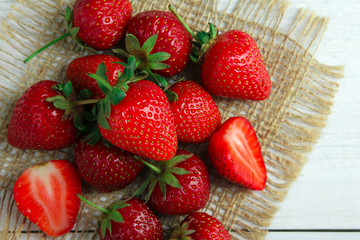 appetizing strawberries on burlap on white wooden background