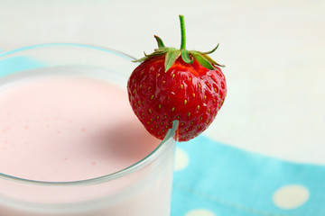 delicious strawberries in a glass with yogurt on napkin on white wooden background