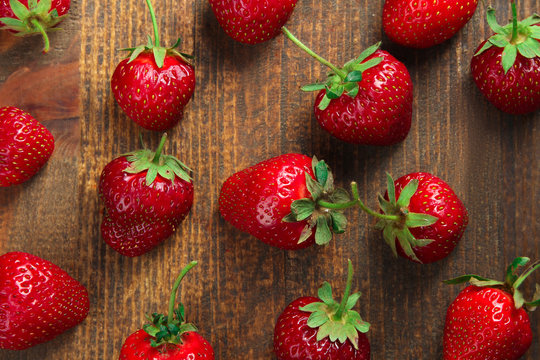 a bunch of ripe delicious strawberries on brown wooden background