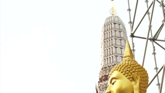 Golden Buddha statue with construction scaffold on the back and pagoda background