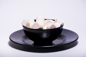 pink marshmellow inside black plate on the white background