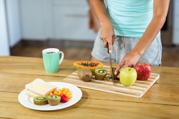 Woman cutting fruits at kitchen counter