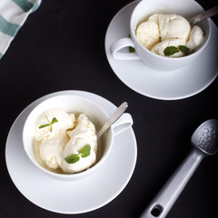 Vanilla ice cream in cup on dark wood background