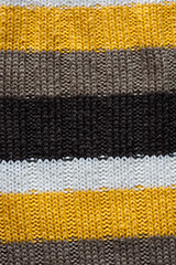 Close up of a wool knitted background with black, brown and yellow