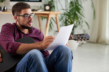 Young man with guitar writing music composition