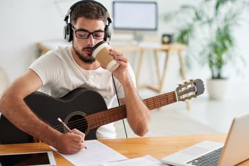 Composer drinking take-out coffee when working on new song