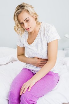 Young woman having stomach pain in bed