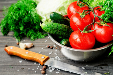 
Fresh juicy ripe summer useful vegetables and greens, red tomatoes , cucumbers , cabbage , lettuce , basil , parsley , dill and salt and spices on a dark wooden background