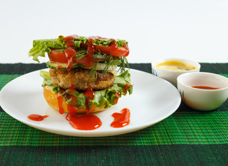 Big beef steak burger with vegetables and herbs on rustic wooden background
