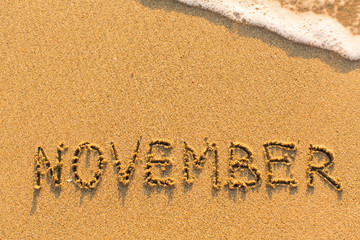 Fototapeta premium November - written by hand on a golden beach sand.
