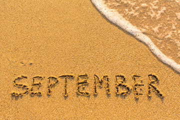 September - written by hand on a golden beach sand.