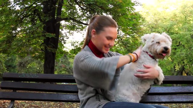 Young woman hugging her white dog in the park outdoor 