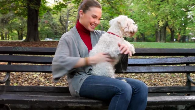 Young woman hugging her white dog in the park outdoor 