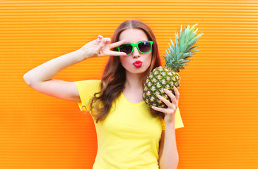Fashion cool girl in sunglasses with pineapple over colorful ora