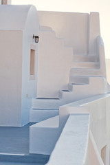 White villa house in Oia with stairs and a flower pot, Santorini