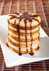 American pancakes with chocolate syrup. Pouring caster sugar.