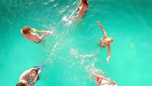 This video is Aerial flight : Happy group of friends enjoying summer pool party splashing in water