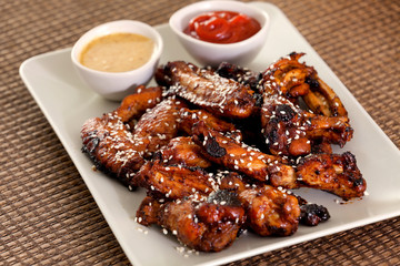 Baked chicken wings with barbecue sauce, sesame seeds, mustard and catchup