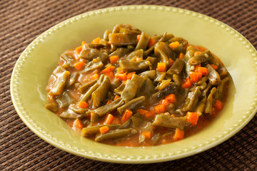 Green beans and carrots stew in a green plate