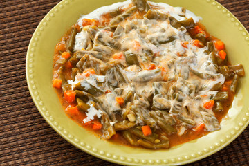 Green beans and carrots stew with yogurt in a green plate