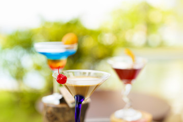 Glasses of cocktails on bright background