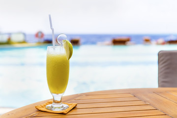 Glasses of color cocktails on pool background