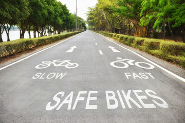 Safety concept, Safe bikes, slow and fast words with white arrow sign marking on road surface in the park for giving directions and separate lanes