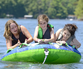 Young teenage girl doing a trick on a float behind a boat.
