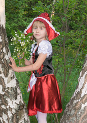 little girl dressed as Little Red Riding Hood in the spring forest