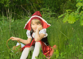 little girl dressed as Little Red Riding Hood in the spring forest