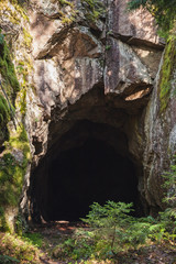 Entrance to dark cave in the rock, vertical
