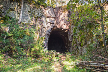 Entrance to dark cave in rock - obrazy, fototapety, plakaty