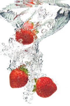 A background of bubbles forming in water after strawberries are dropped into it.