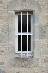 A small window with bars set in a stone wall
