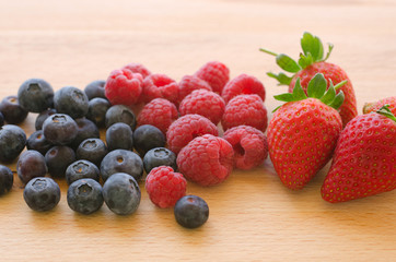 Blueberries, raspberries and strawberries on a wooden background