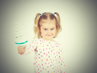 Little girl shows a large energy-saving light bulbs.