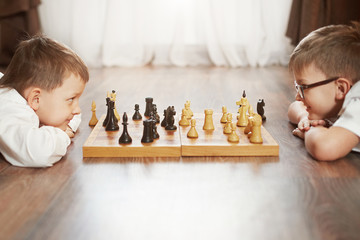 Two boy playing chess, studio, gray background © sergmakssmol