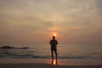 Landscape of cloudy sky and sea that has fisherman who hold fishnet stand on the beach in morning ; Songkhla Thailand