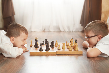 Two boy playing chess, studio, gray background © sergmakssmol