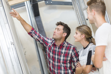 Young apprentice with professional plasterer