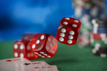 Red dice rotates and will fall 7, casino chips, cards on green felt