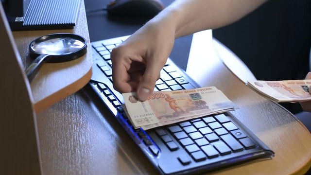 The man in the office counting money at the computer table