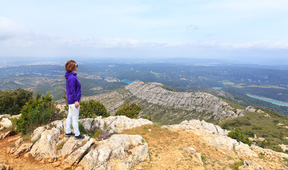 young woman standing on a mountain and looking at a valley