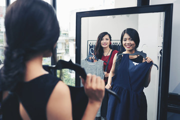 Young smiing woman with a dress looking at herself in mirror