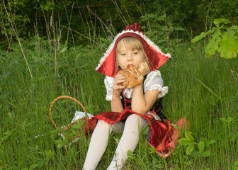 little girl dressed as Little Red Riding Hood in the spring forest