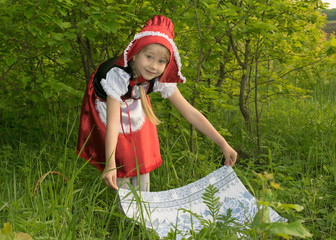little girl dressed as Little Red Riding Hood in the spring forest