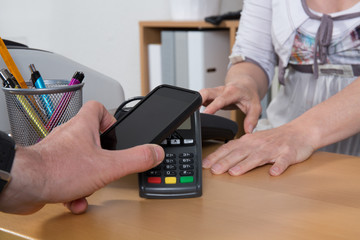 Male paying for good with NFC technology on mobile phone