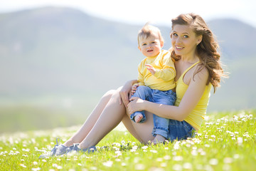 Fototapeta premium Mother with little son in a flower field 